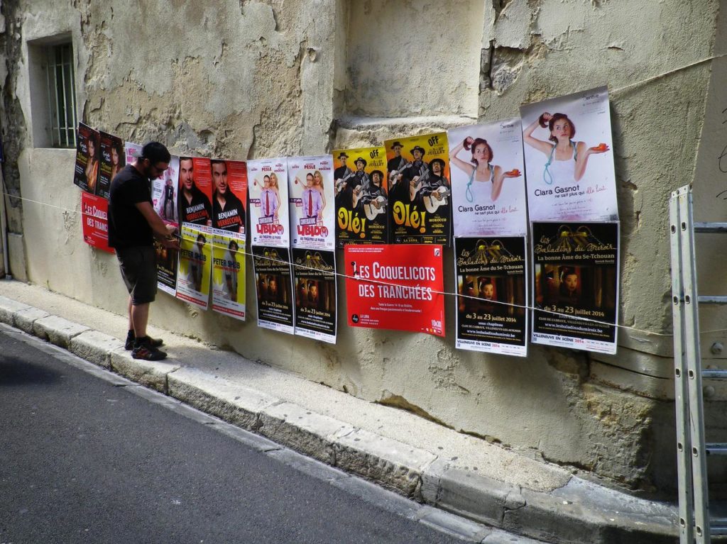 Des affiches de spectacles de théâtre sur un mur pendant le festival d'Avignon 