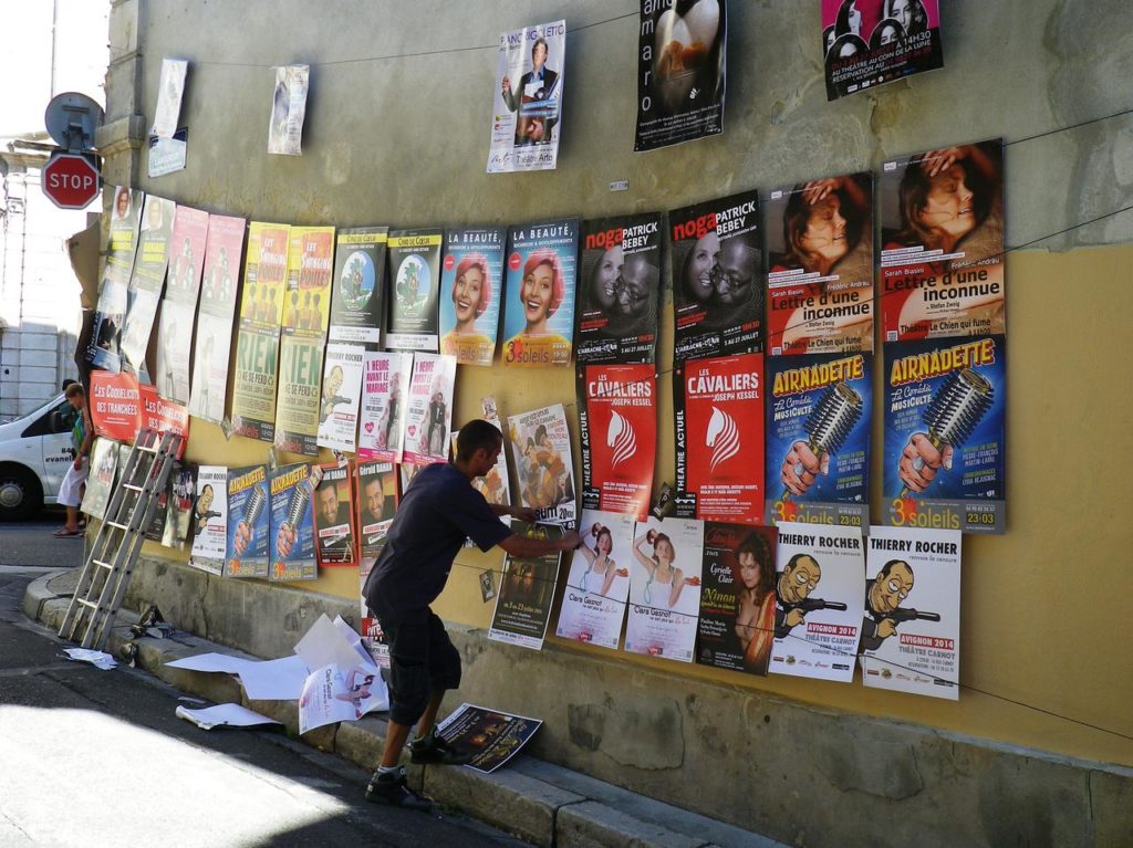 Pose d'affiches sur un mur pendant le festival d'Avignon pour les spectacles de théâtre