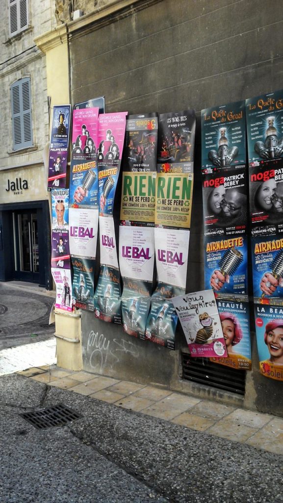 Des affiches de spectacles de théâtre sur un mur pendant le festival d'Avignon 