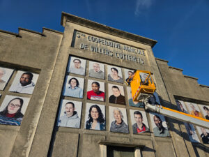 Installation en hauteur avec une nacelle sur l'ancienne façade la coopérative agricole de Villers-Cotterêts de visage pour une intervention socio-culturelle de la Cité internationale de la langue française.