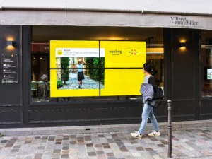 Écran digital sur la devanture d'une agence immobilière en ville