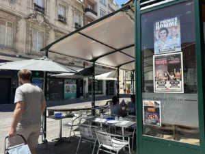 Affiches de spectacles du Festival OFF posées sur la devanture vitrée d'un restaurant à Avignon