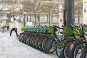 Station Vélib' avec des vélos en libre-service alignés sur un trottoir parisien, habillés aux couleurs d'une campagne publicitaire