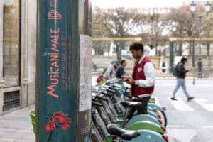 Totem d'une station Vélib' habillé aux couleurs de l'exposition Musicanimale de la Philharmonie de Paris, avec des vélos et un utilisateur en arrière-plan