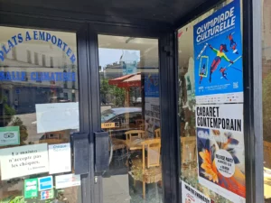 Affiches des spectacles Olympia Culturelle et Cabaret Contemporain posées au ruban adhésif sur la vitrine d'un commerce