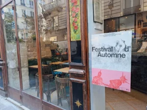 Affiche du Festival d'Automne à Paris, posée au ruban adhésif, sur la vitrine d'un café parisien.