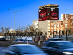 Grand panneau publicitaire Renault Clio en bord du périphérique parisien, sur la Tour ESSOR, face au Parc de la Villette, avec la circulation dense au premier plan, sur la plus grande toile d'affichage de France : 2 133 m²