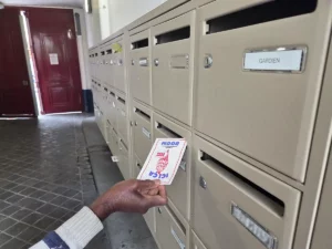 Diffusion d'un flyer publicitaire dans la boîte aux lettres d'un immeuble parisien.