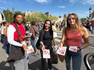 Trois distributrices tendent des flyers pour le spectacle Kinky Boots aux passants dans la rue lors de la Gay Pride parisienne.
